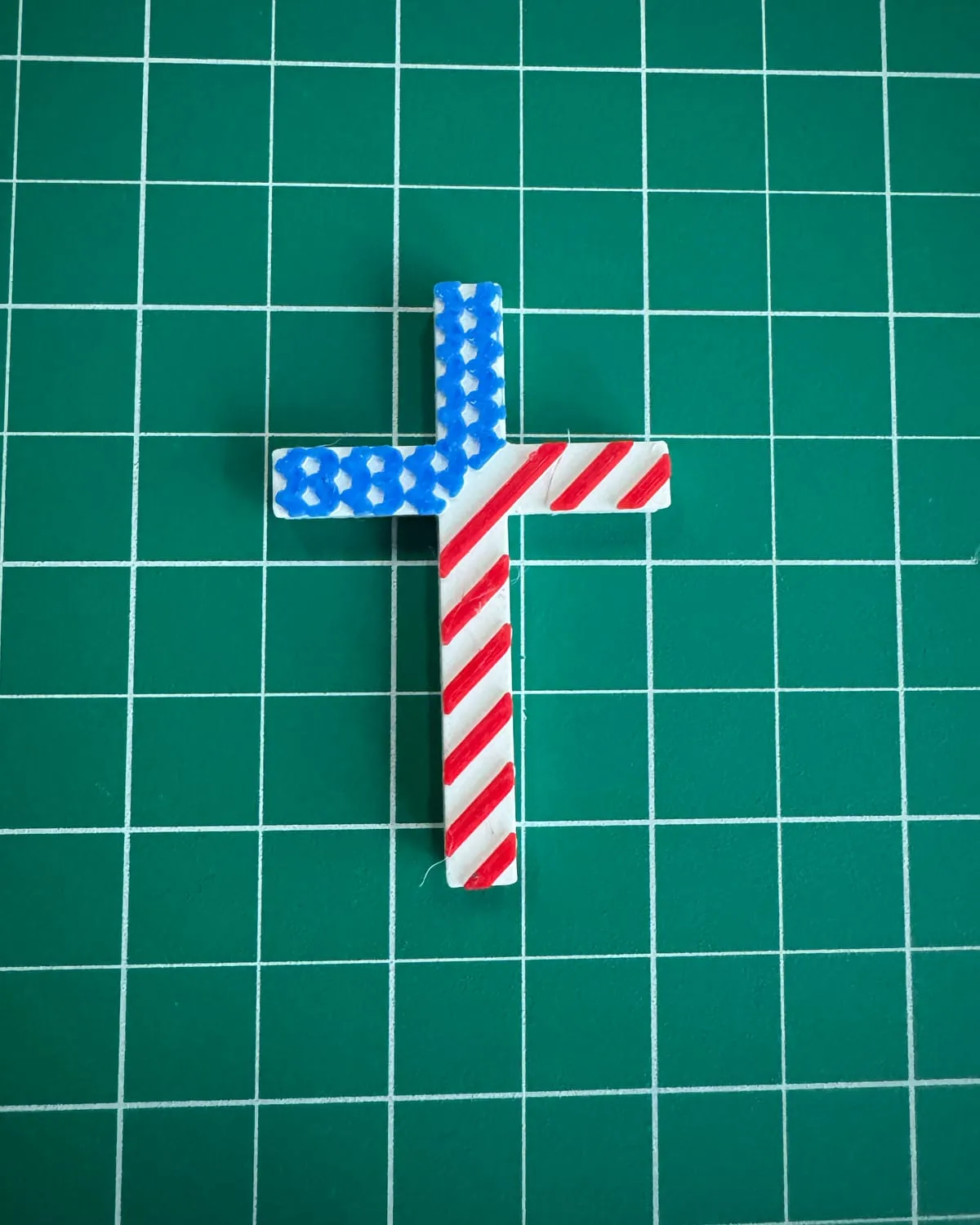 A 3D-printed cross patterned like the American flag, with blue stars and red stripes