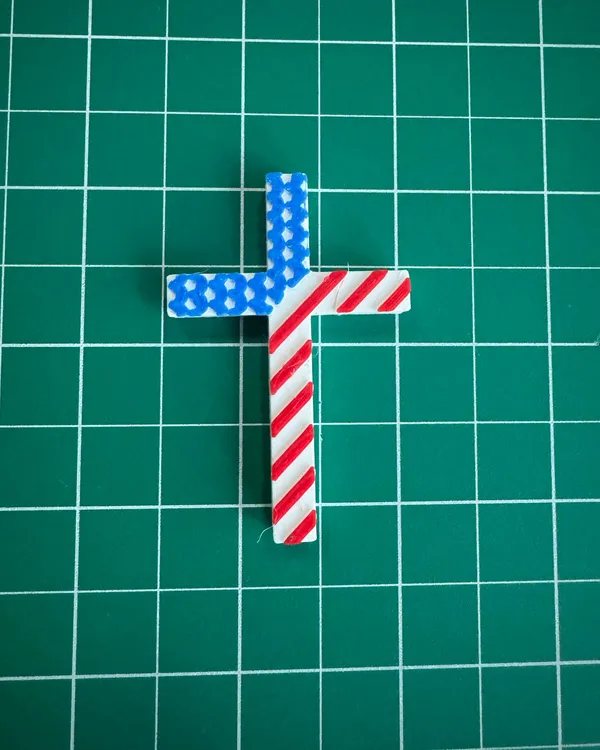 A 3D-printed cross patterned like the American flag, with blue stars and red stripes