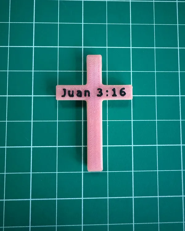 A rose-colored 3D-printed cross with "Juan 3:16" in raised letters on the crossbar